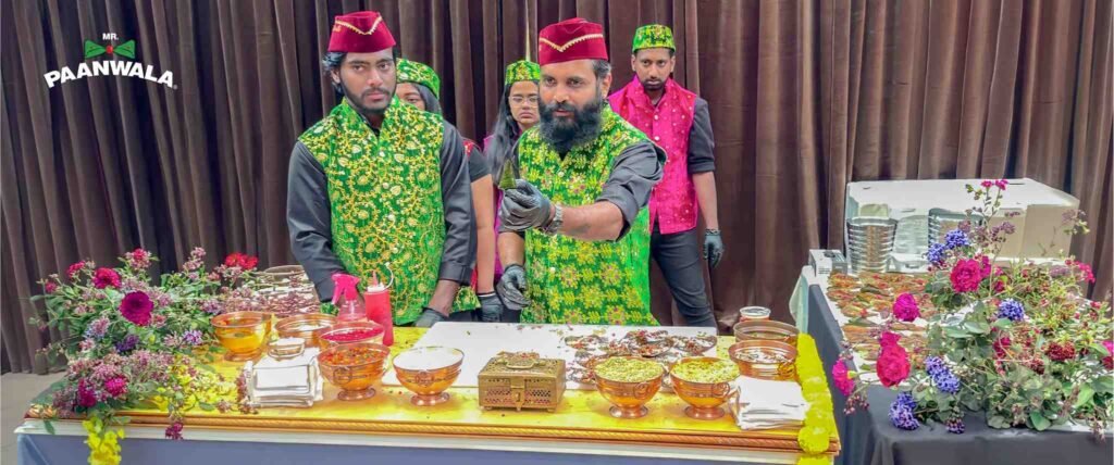 Mr.Paanwala staff preparing paan at a decorated counter while following hygiene practices and wearing gloves.